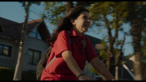 Girl in a red polo shirt riding a bike smiling 