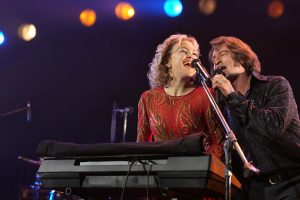 Two people signing together on stage with on playing a keyboard